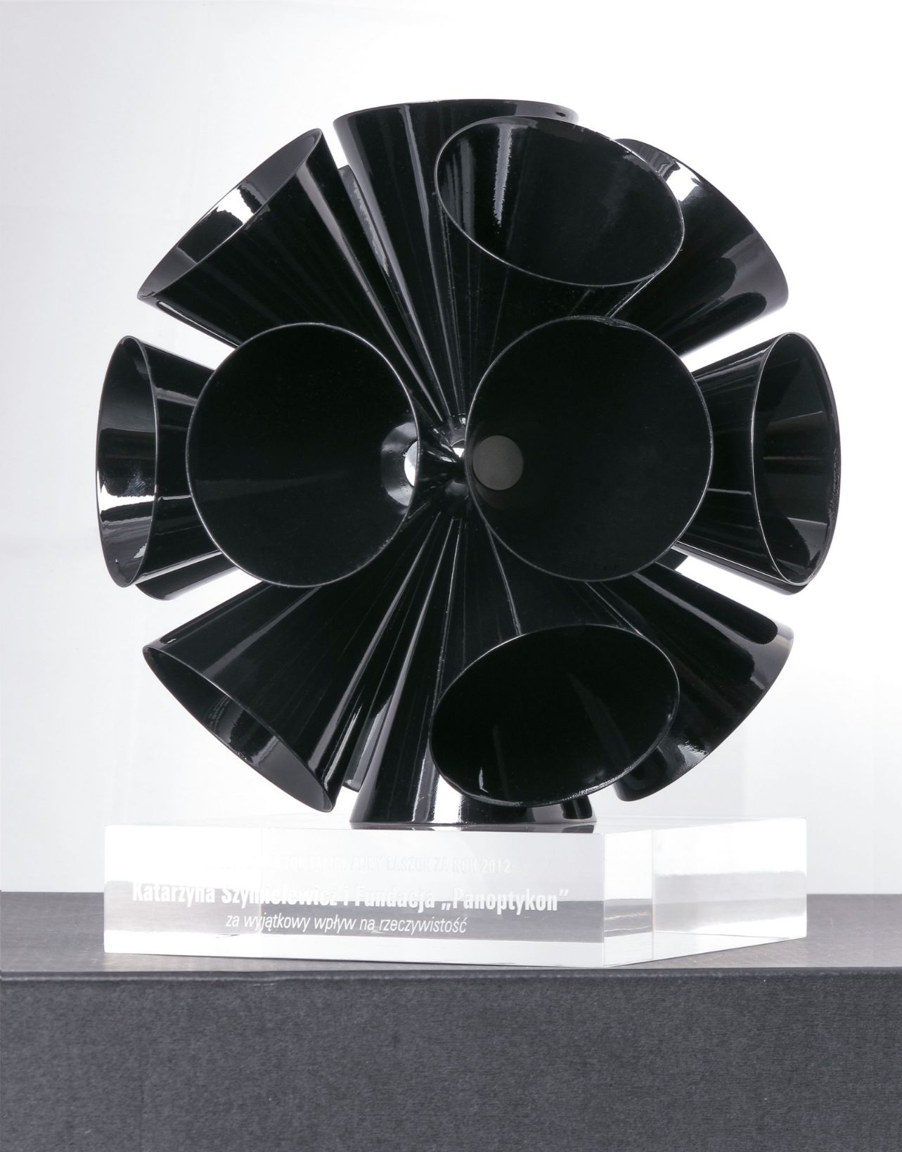 Artystyczna statuetka na zamówienie zaprojektowana jako nagroda dla TOK FM, łącząca rzeźbiarską formę z precyzją wykonania. Konstrukcja z mosiądzu, formowana i lutowana ręcznie, została wykończona w czarnym połysku i zestawiona z transparentną podstawą z grawerowanej pleksi.